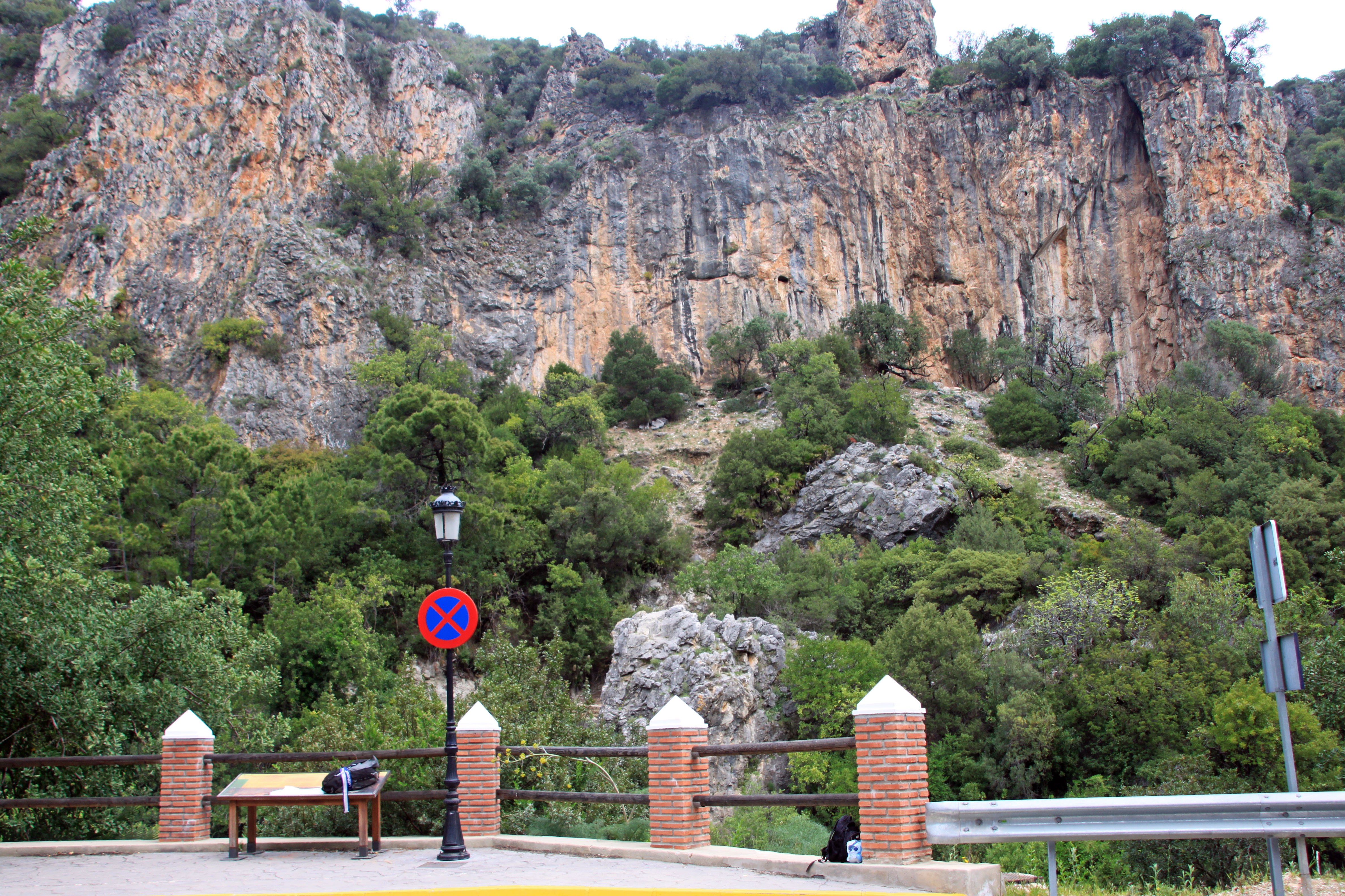 Blick auf eine Felsformation in Benahavís, Spanien, mit üppigem Grün und einem Parkschild.